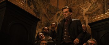 Movie still from “Harry Potter and the Goblet of Fire” (2005), directed by Mike Newell – A group of men sitting next to each other in front of a painting; Medium shot, Low angle