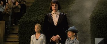 Movie still from “Harry Potter and the Goblet of Fire” (2005), directed by Mike Newell – A woman standing between two young girls in front of a bush; Medium shot, Low angle