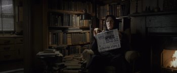 Movie still from “Harry Potter and the Half-Blood Prince” (2009), directed by David Yates – A woman sitting in a chair holding a newspaper; Medium shot, High angle