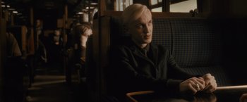 Movie still from “Harry Potter and the Half-Blood Prince” (2009), directed by David Yates – A man sitting in a chair on a train; Medium shot, Over the shoulder angle