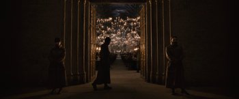 Movie still from “Harry Potter and the Half-Blood Prince” (2009), directed by David Yates – A person walking through a hallway with lights in the background; Wide shot, High angle