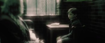 Movie still from “Harry Potter and the Half-Blood Prince” (2009), directed by David Yates – A young boy sitting in a chair in front of a window; Medium shot, Over the shoulder angle