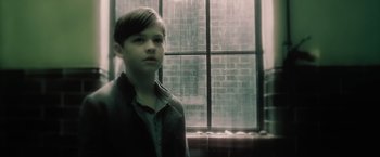 Movie still from “Harry Potter and the Half-Blood Prince” (2009), directed by David Yates – A young boy standing in front of a window in the rain; Close Up shot, Low angle