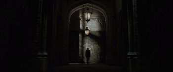 Movie still from “Harry Potter and the Half-Blood Prince” (2009), directed by David Yates – A person is standing in the dark under an arch; Extreme Wide shot, Low angle