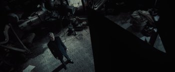 Movie still from “Harry Potter and the Half-Blood Prince” (2009), directed by David Yates – A man standing in front of a camera in a dark room; Wide shot, Overhead angle