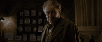 Movie still from “Harry Potter and the Half-Blood Prince” (2009), directed by David Yates – An older man in a suit and tie in front of a wall; Close Up shot, Over the shoulder angle