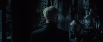 Movie still from “Harry Potter and the Half-Blood Prince” (2009), directed by David Yates – A man in a black suit standing in front of an ornate door; Close Up shot, Over the shoulder angle
