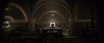 Movie still from “Harry Potter and the Half-Blood Prince” (2009), directed by David Yates – A man standing at a table in a room; Wide shot, Low angle