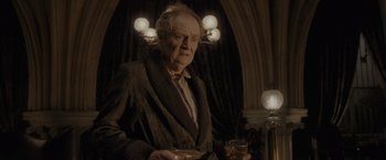 Movie still from “Harry Potter and the Half-Blood Prince” (2009), directed by David Yates – An older man holding a glass of wine in his hands; Medium shot, Over the shoulder angle