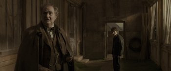 Movie still from “Harry Potter and the Half-Blood Prince” (2009), directed by David Yates – A man standing next to another man in a dark room; Medium shot, Over the shoulder angle