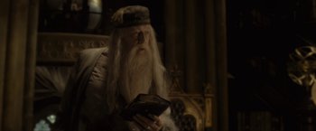 Movie still from “Harry Potter and the Half-Blood Prince” (2009), directed by David Yates – A man with long white hair is holding an open book; Medium shot, High angle