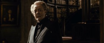 Movie still from “Harry Potter and the Half-Blood Prince” (2009), directed by David Yates – An old man in a suit standing next to a bookshelf; Close Up shot, Low angle