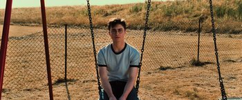 Movie still from “Harry Potter and the Order of the Phoenix” (2007), directed by David Yates – A man sitting on a swing in a field; Wide shot, High angle