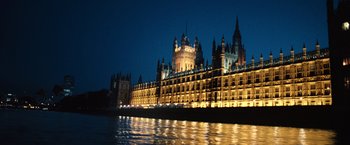 Movie still from “Harry Potter and the Order of the Phoenix” (2007), directed by David Yates – A large building lit up at night next to a body of water; Extreme Wide shot, Low angle