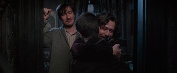 Movie still from “Harry Potter and the Order of the Phoenix” (2007), directed by David Yates – Two men hugging each other while another man watches; Medium shot, Over the shoulder angle
