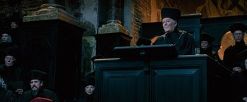 Movie still from “Harry Potter and the Order of the Phoenix” (2007), directed by David Yates – A man and a woman are sitting in front of a podium; Medium shot, Low angle