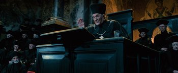 Movie still from “Harry Potter and the Order of the Phoenix” (2007), directed by David Yates – An old man sitting at a table in front of a glass of water; Medium shot, Low angle