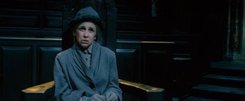Movie still from “Harry Potter and the Order of the Phoenix” (2007), directed by David Yates – A woman sitting on top of a bench wearing a hat; Medium shot, High angle