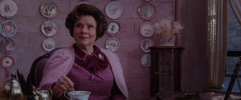 Movie still from “Harry Potter and the Order of the Phoenix” (2007), directed by David Yates – An older woman sitting in front of plates on the wall; Medium shot, Over the shoulder angle