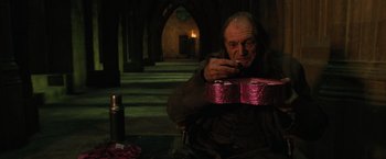 Movie still from “Harry Potter and the Order of the Phoenix” (2007), directed by David Yates – An old man smoking a cigarette while holding a pink guitar case; Medium shot, High angle