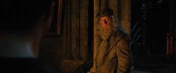 Movie still from “Harry Potter and the Order of the Phoenix” (2007), directed by David Yates – A man with a beard and a hat is leaning against a pillar; Medium shot, Over the shoulder angle