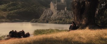 Movie still from “Harry Potter and the Order of the Phoenix” (2007), directed by David Yates – A person sitting on the grass near a body of water; Extreme Wide shot, High angle