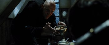Movie still from “Harry Potter and the Prisoner of Azkaban” (2004), directed by Alfonso Cuarón – A bald man is holding a bowl of food in his hands; Medium shot, Low angle