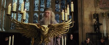 Movie still from “Harry Potter and the Prisoner of Azkaban” (2004), directed by Alfonso Cuarón – An old man with a long white beard is holding an owl in front of candles; Medium shot, Low angle