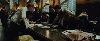 Movie still from “Harry Potter and the Prisoner of Azkaban” (2004), directed by Alfonso Cuarón – A group of people sitting at a table reading books; Medium shot, High angle