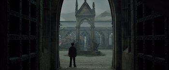 Movie still from “Harry Potter and the Prisoner of Azkaban” (2004), directed by Alfonso Cuarón – A man standing in front of a building with a fountain; Wide shot, Low angle