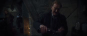 Movie still from “Harry Potter and the Prisoner of Azkaban” (2004), directed by Alfonso Cuarón – A man in a suit and tie holding a bottle of wine; Medium shot, High angle