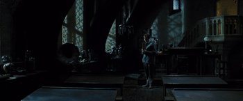 Movie still from “Harry Potter and the Prisoner of Azkaban” (2004), directed by Alfonso Cuarón – A man standing in a dark room holding a cell phone; Wide shot, High angle