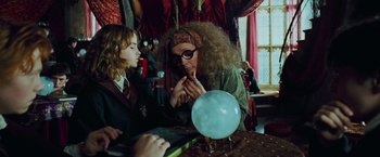Movie still from “Harry Potter and the Prisoner of Azkaban” (2004), directed by Alfonso Cuarón – A woman in a wig and glasses looking at a crystal ball; Medium shot, Over the shoulder angle