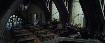Movie still from “Harry Potter and the Prisoner of Azkaban” (2004), directed by Alfonso Cuarón – A man standing in a room with many wooden benches; Extreme Wide shot, High angle
