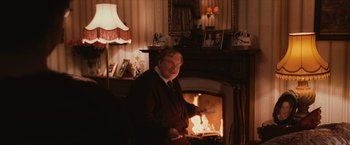 Movie still from “Harry Potter and the Sorcerer's Stone” (2001), directed by Chris Columbus – A man standing in front of a fireplace holding a knife; Medium shot, Over the shoulder angle