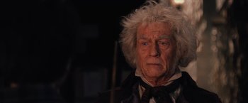 Movie still from “Harry Potter and the Sorcerer's Stone” (2001), directed by Chris Columbus – An older man with white hair and a black tie; Close Up shot, Low angle