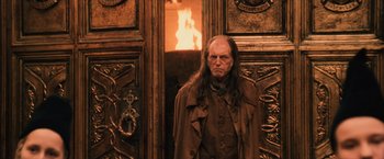 Movie still from “Harry Potter and the Sorcerer's Stone” (2001), directed by Chris Columbus – A man with long hair standing in front of a fireplace; Medium shot, Over the shoulder angle