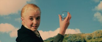 Movie still from “Harry Potter and the Sorcerer's Stone” (2001), directed by Chris Columbus – A young girl holding a glass ball in front of a sky background; Close Up shot, Low angle