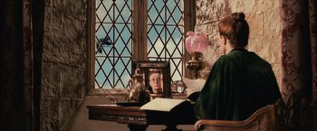 Movie still from “Harry Potter and the Sorcerer's Stone” (2001), directed by Chris Columbus – A woman sitting at a table with a picture of herself; Medium shot, Over the shoulder angle