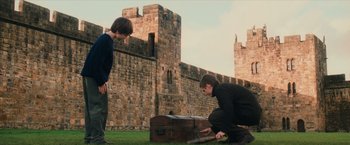 Movie still from “Harry Potter and the Sorcerer's Stone” (2001), directed by Chris Columbus – Two people are looking at a chest in a field; Wide shot, High angle