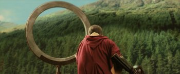 Movie still from “Harry Potter and the Sorcerer's Stone” (2001), directed by Chris Columbus – A man standing in front of a large circular object; Wide shot, Over the shoulder angle