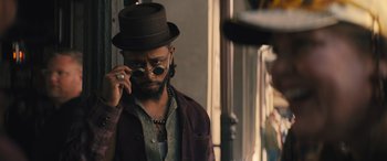 Movie still from “Haunted Mansion” (2023), directed by Justin Simien – A man in a hat and sunglasses talking on a cell phone; Close Up shot, Over the shoulder angle