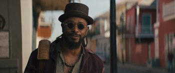 Movie still from “Haunted Mansion” (2023), directed by Justin Simien – A man wearing a hat and sunglasses standing on the street; Close Up shot, Low angle