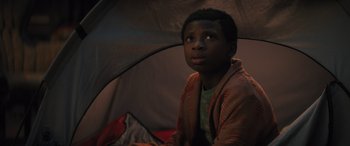 Movie still from “Haunted Mansion” (2023), directed by Justin Simien – A young boy sitting under a tent looking up at the sky; Close Up shot, Low angle