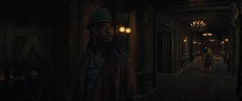 Movie still from “Haunted Mansion” (2023), directed by Justin Simien – A man wearing a hat standing next to a building; Medium shot, Low angle