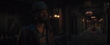 Movie still from “Haunted Mansion” (2023), directed by Justin Simien – A man wearing a hat standing in front of a building; Close Up shot, Low angle