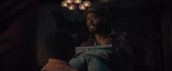 Movie still from “Haunted Mansion” (2023), directed by Justin Simien – A man wearing a hat is talking to another man; Medium shot, Over the shoulder angle