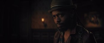 Movie still from “Haunted Mansion” (2023), directed by Justin Simien – A man wearing a hat and a tie; Close Up shot, Over the shoulder angle