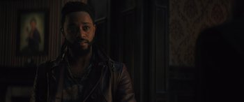 Movie still from “Haunted Mansion” (2023), directed by Justin Simien – A man wearing a leather jacket standing next to a building; Close Up shot, Over the shoulder angle