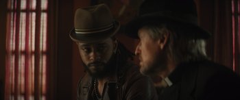 Movie still from “Haunted Mansion” (2023), directed by Justin Simien – A man wearing a hat and a leather jacket; Close Up shot, Over the shoulder angle